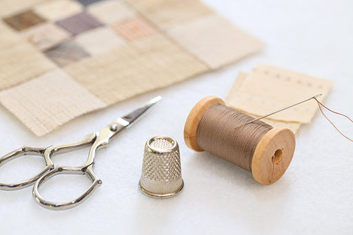 patchwork quilt squares with needle, thread, thimble and scissors