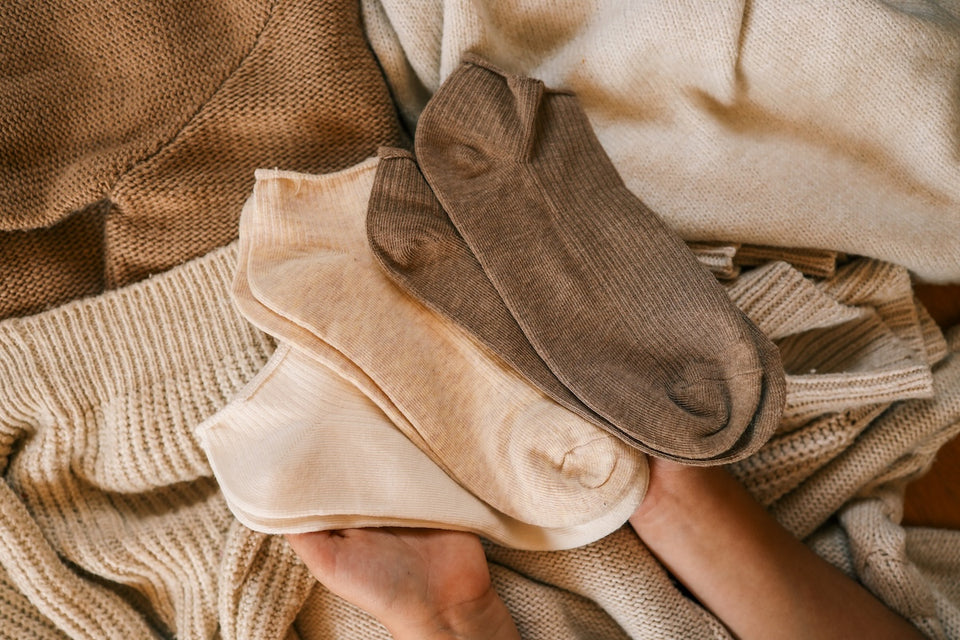 a few pairs of socks and woolen knits in shades of cream and brown