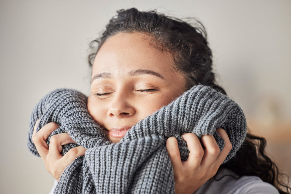 A happy woman enjoying the feel of freshly laundered pure wool against her face