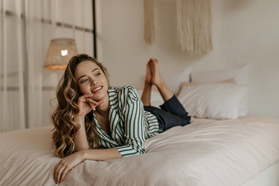 a woman lying on her bed dressed in a white and green striped shirt