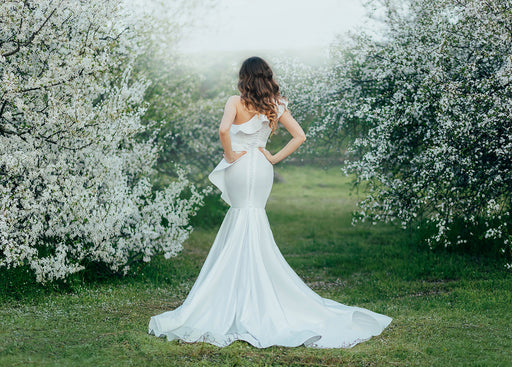 the back view of a bride wearing a wedding dress with a mermaid skirt